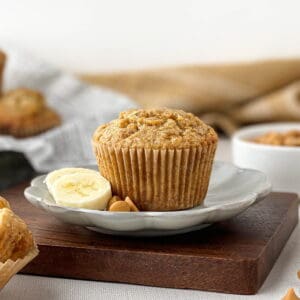 Butterscotch banana muffin on a plate with butterscotch chips and banana slices.