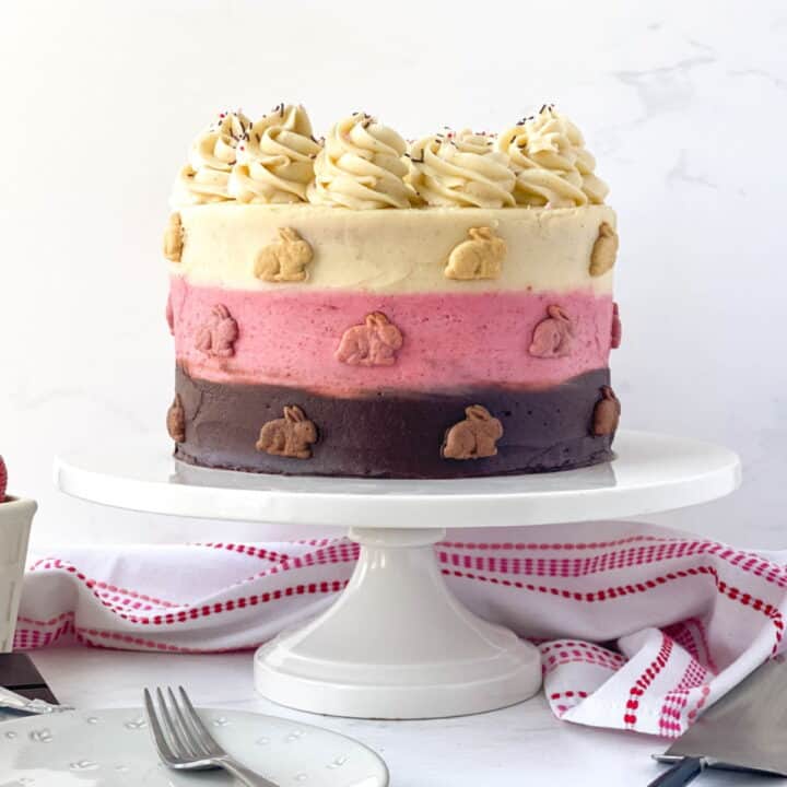 Neapolitan Cake with graham bunnies on a white cake stand.