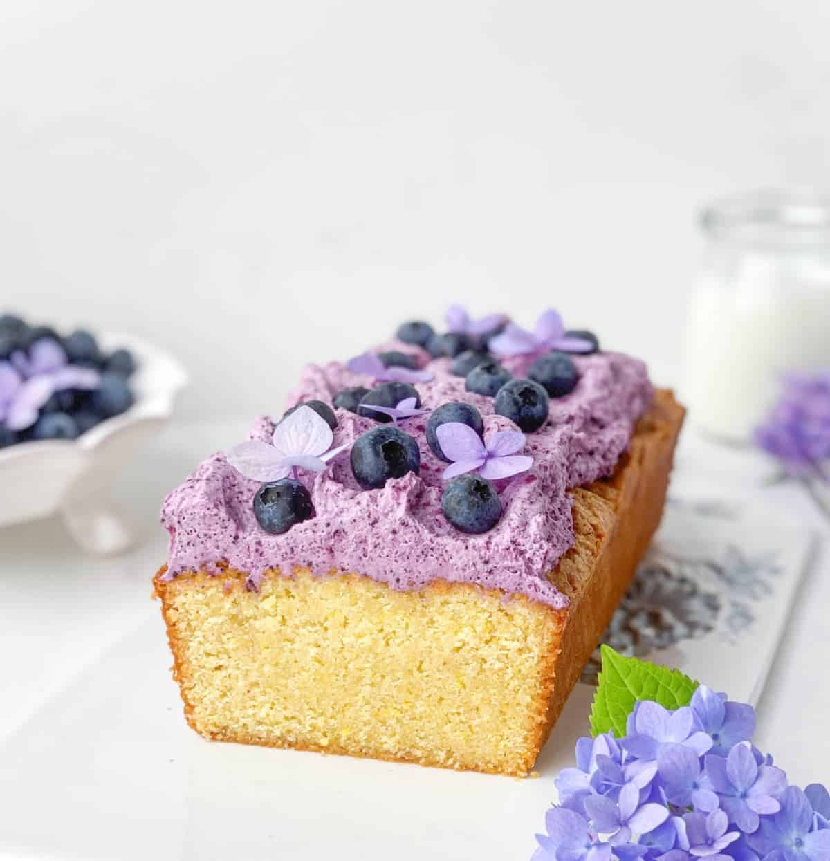 Blueberry Cornmeal Pound Cake on a white serving tray with purple blueberry mascarpone topping.