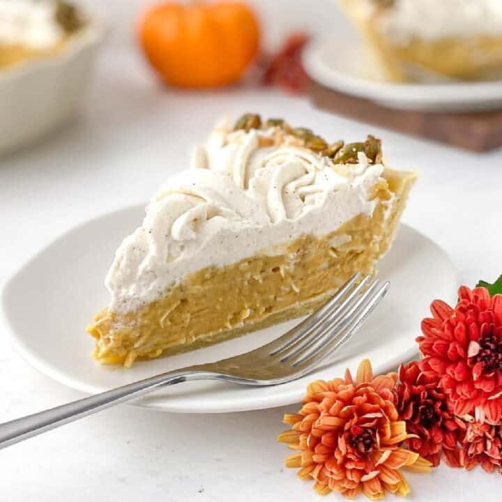 Pumpkin Coconut Pie on a white plate with fall mums nearby.