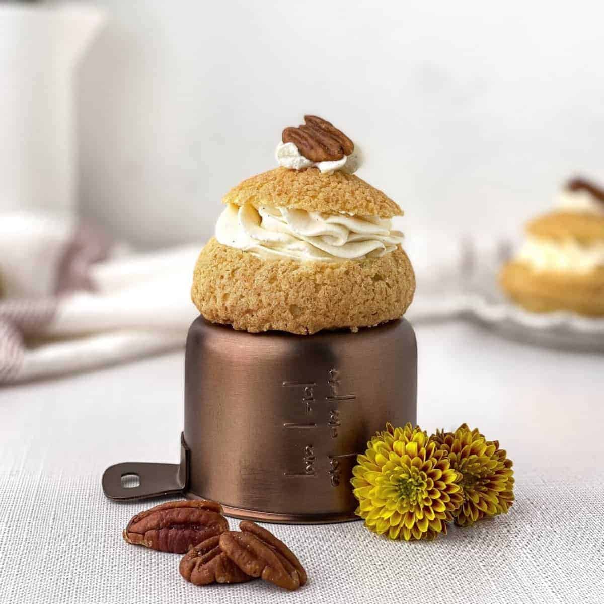 Pecan pie cream puff on top of measuring cup.