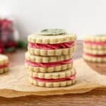 Stack of three Cranberry Sage Cookies on parchment paper with a candied sage leaf on top.