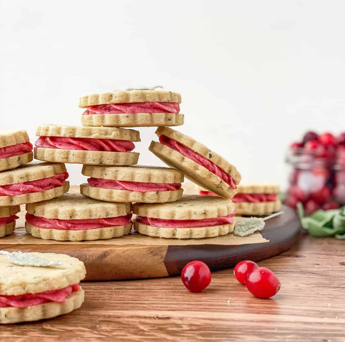 Cranberry Sage Cookies stacked on a serving board with cranberries in the background