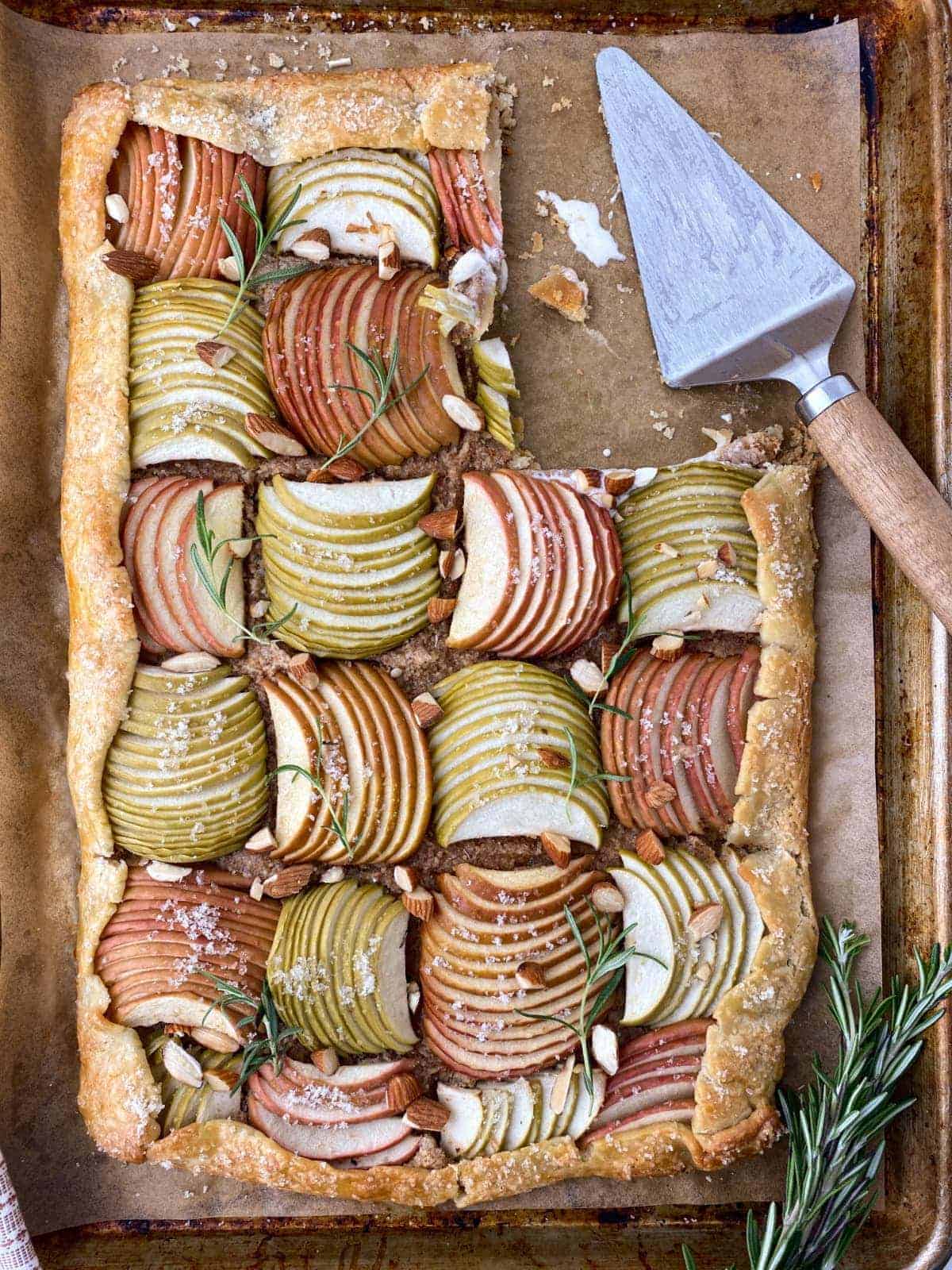 Rosemary Almond Apple Galette on a baking sheet with a slice missing