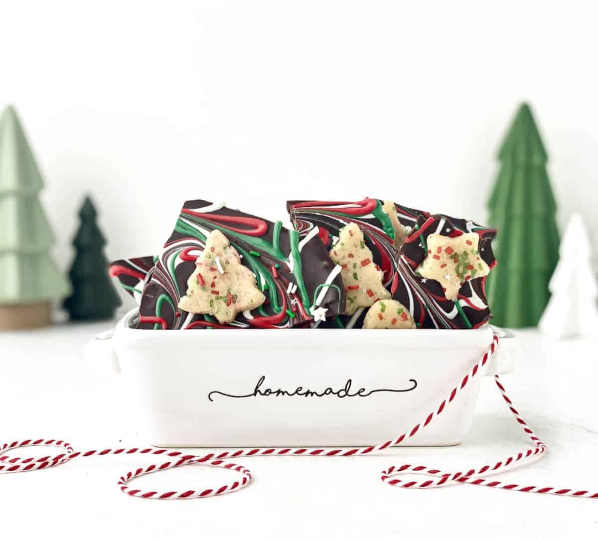Sugar Cookie Dough Bark in a ceramic tray with Christmas trees in the background
