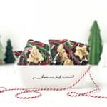 Sugar Cookie Dough Bark in a white container with small Christmas trees nearby.