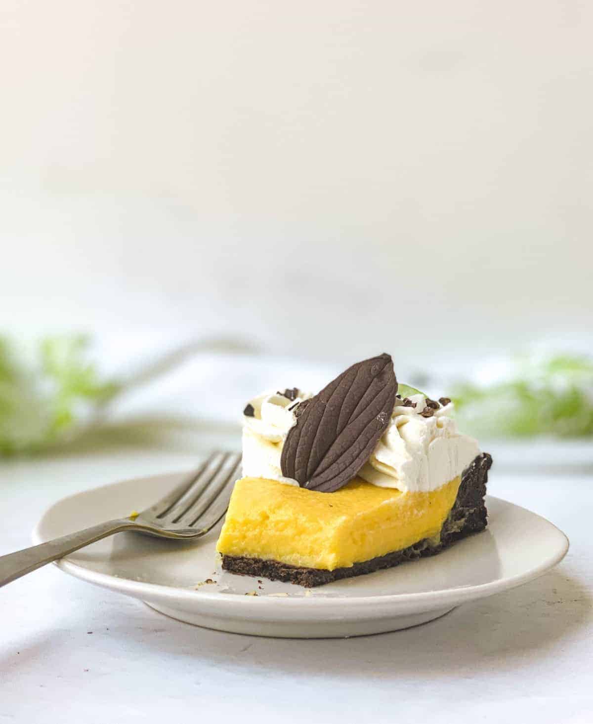 A partially eaten slice of Chocolate Mango Tart on a white plate with a fork next to it