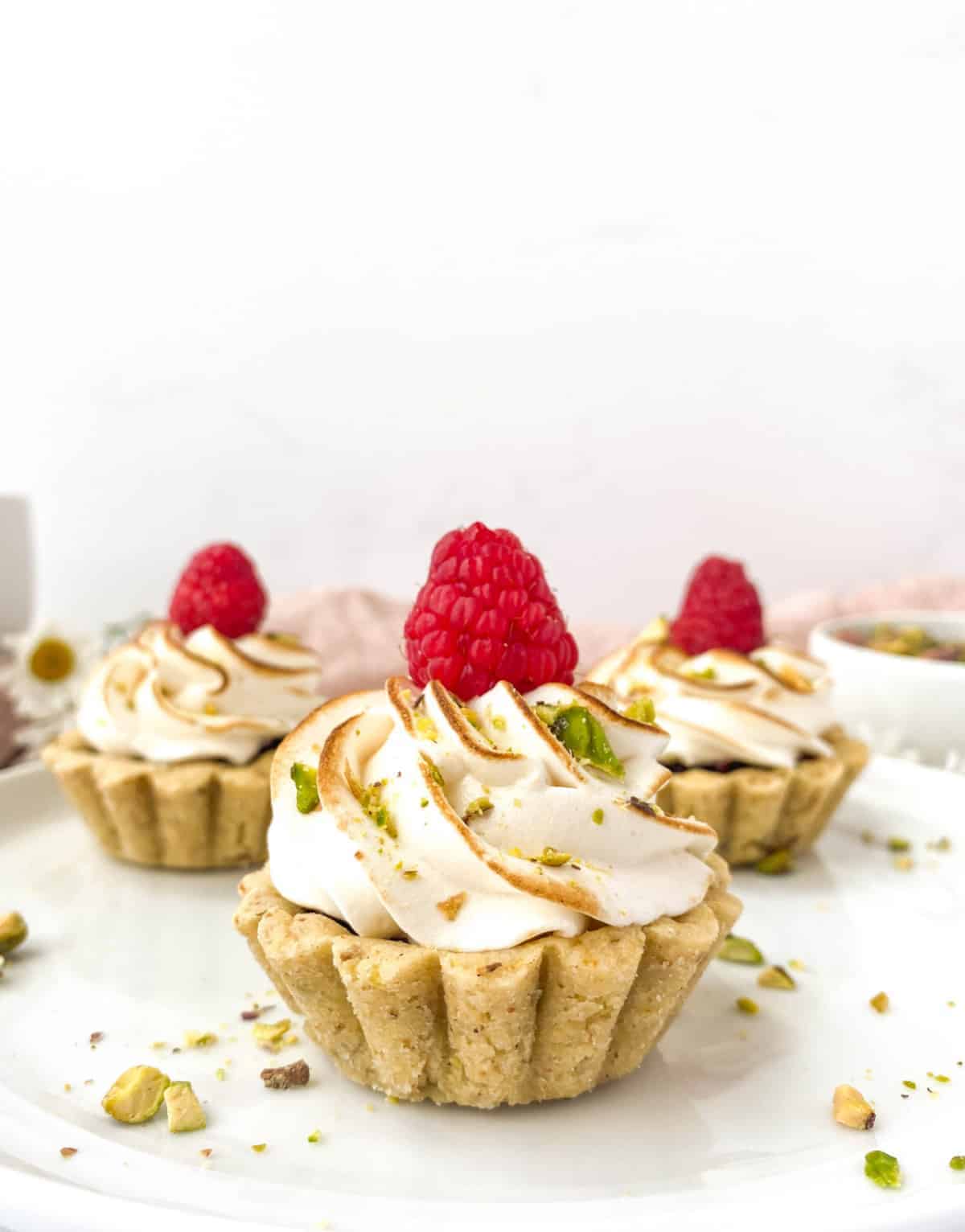 Close up of Raspberry Pistachio Tartlet with more tartlets in the background