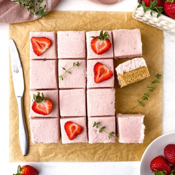 Top view of sliced Strawberry Thyme Blondies with cut strawberries and sprigs of thyme on top.