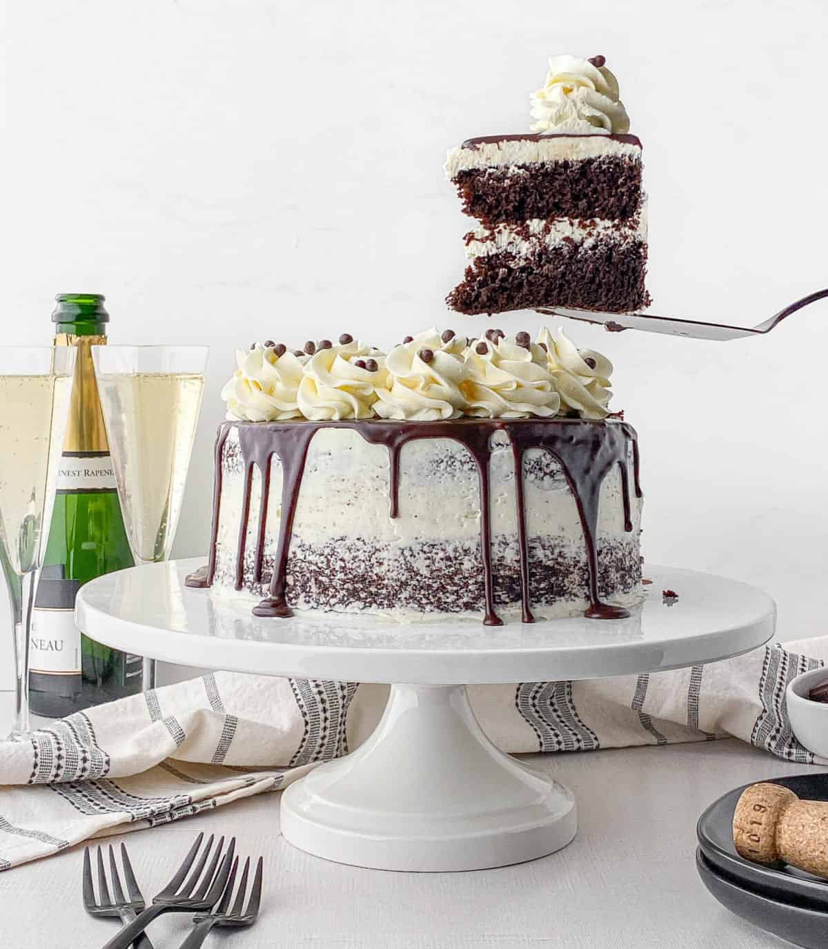 A slice of Chocolate Champagne Cake on a cake server next to the rest of the cake.