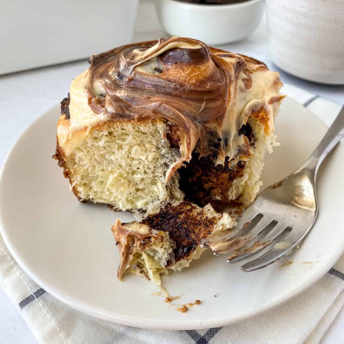 Chocolate Caramel Sweet Roll on a white plate with a fork next to it.