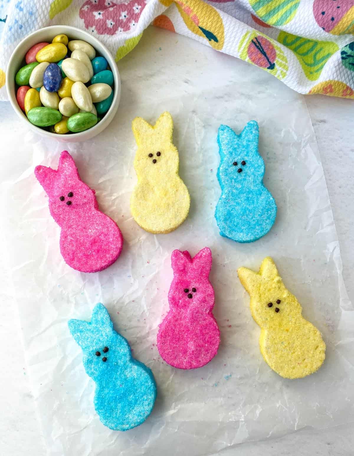 Bunny-shaped Homemade Peeps on parchment with a bowl of jellybeans nearby.