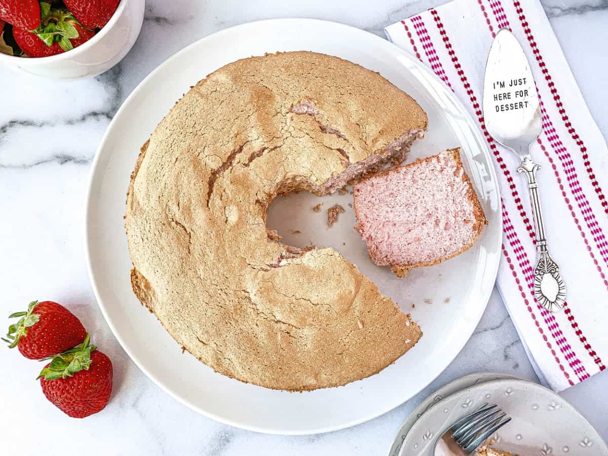 Top view of sliced Strawberry Angel Food Cake on a white cake plate.