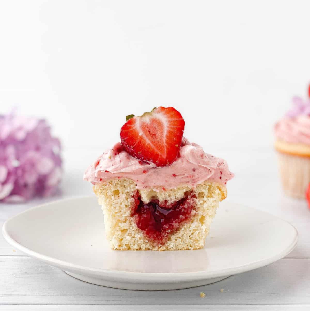 Strawberry Filled Cupcake cut in half to show the strawberry jam inside.
