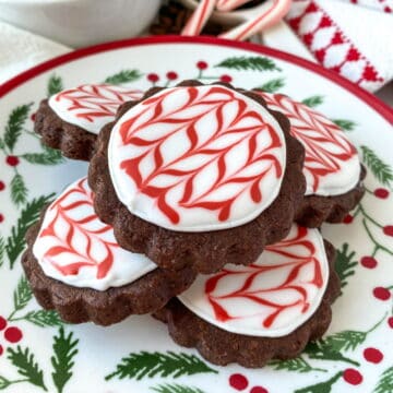 Peppermint Mocha Cookies stacked on a holiday plate with candy canes in the background.