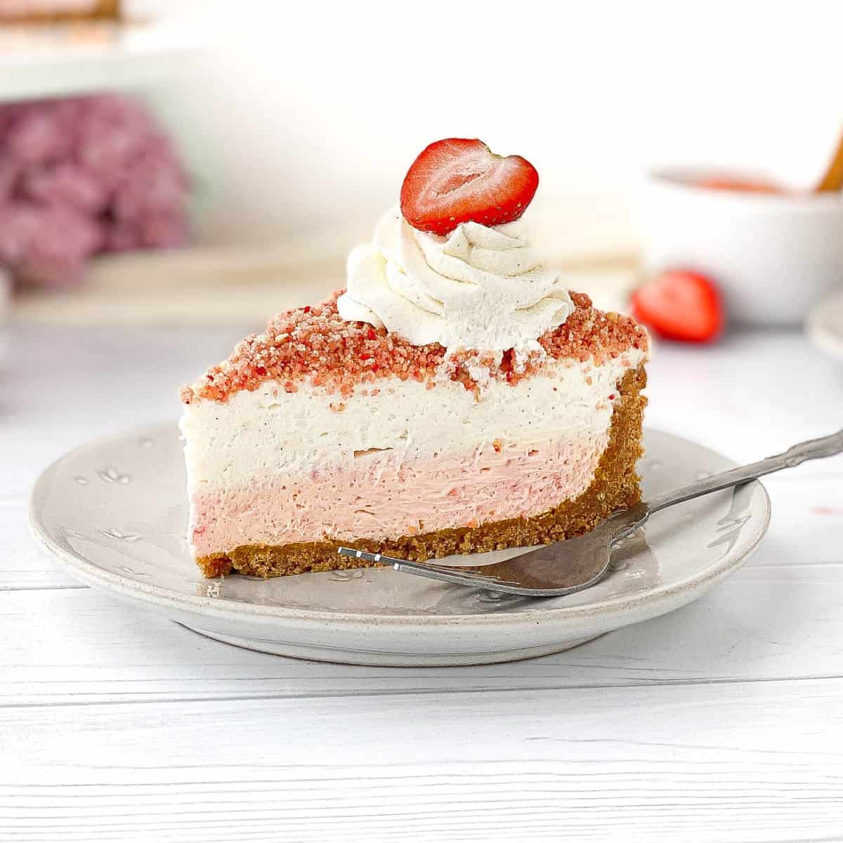 Slice of Strawberry Crunch Cheesecake on white plate.
