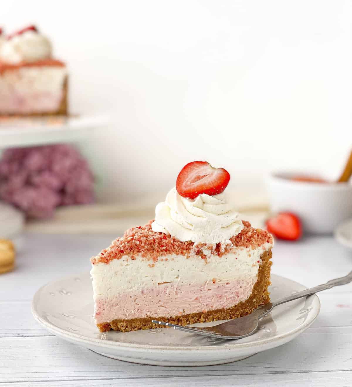 Slice of Strawberry Crunch Cheesecake on a white plate.