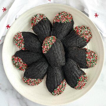 Chocolate Madeleines with Christmas sprinkles on a white plate.