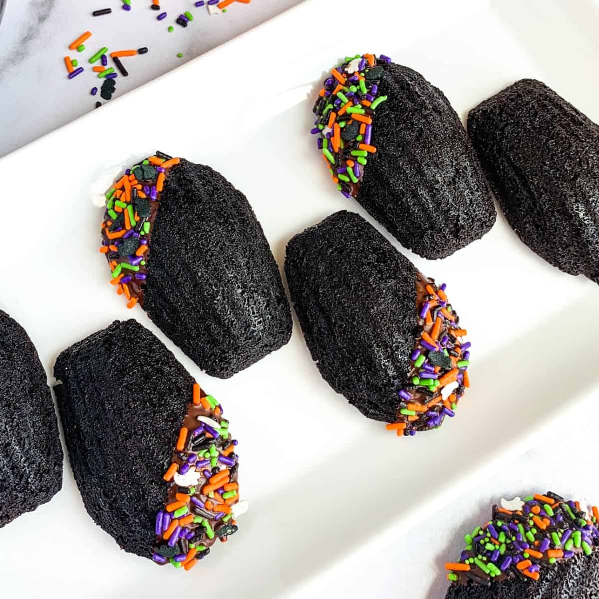 Chocolate Madeleines with Halloween sprinkles on a white plate.