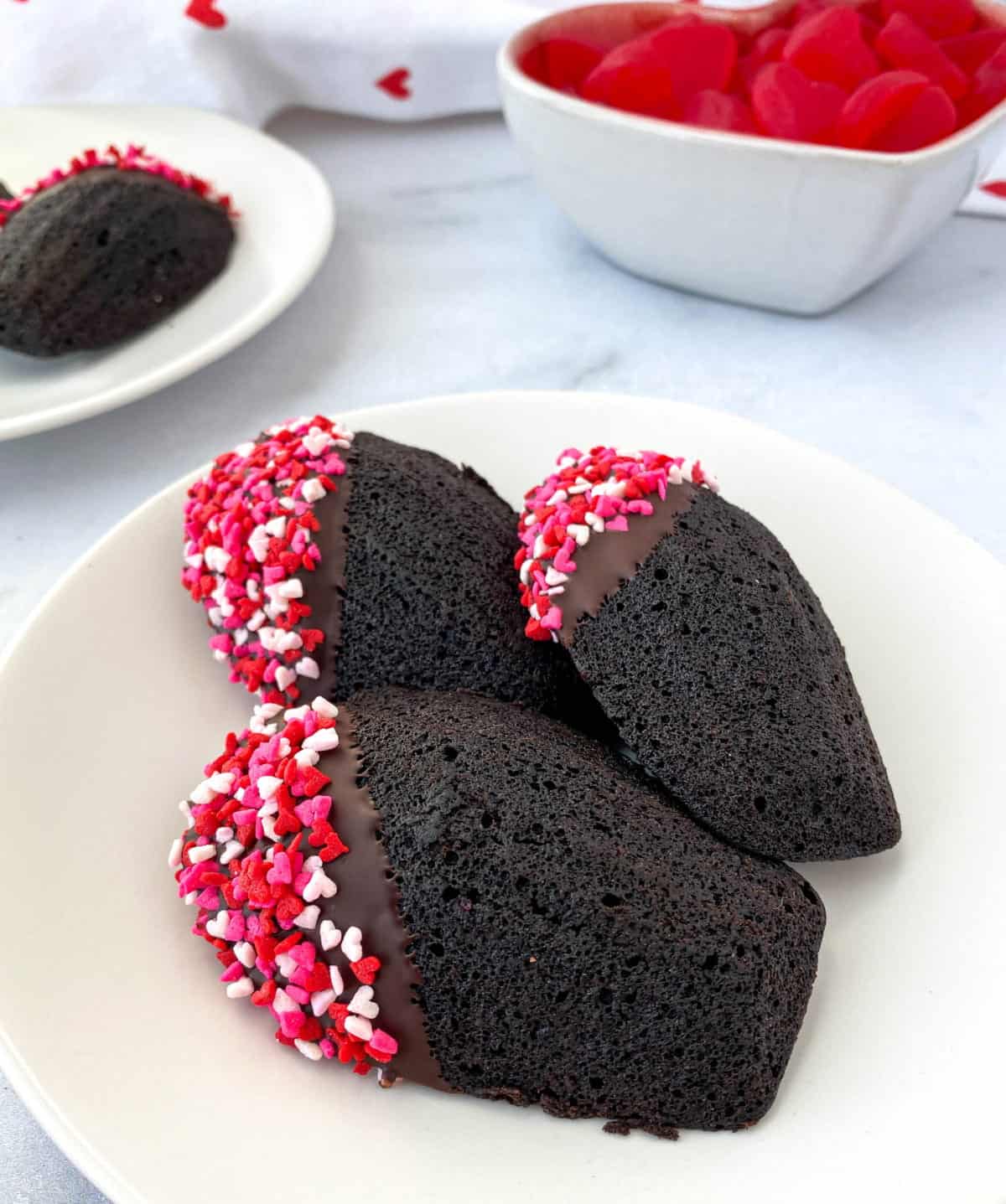 Chocolate Madeleines with valentine's day sprinkles on a white plate.