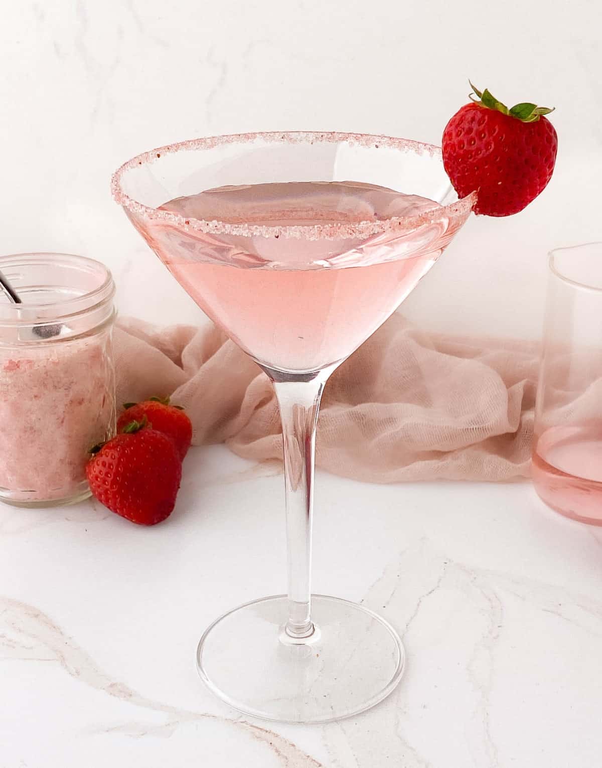 Pink cocktail with Strawberry Sugar and a fresh strawberry on the rim.