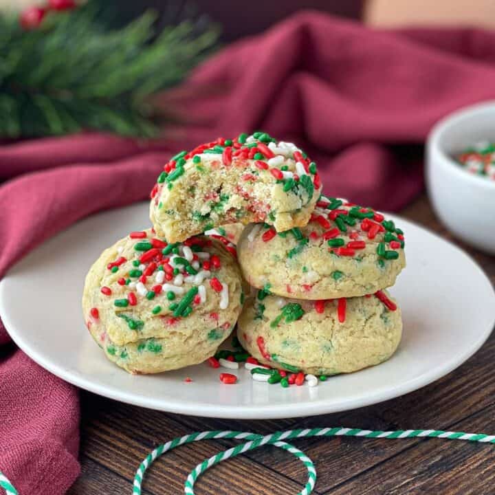 Christmas Sprinkle Cookies stacked on a white plate.