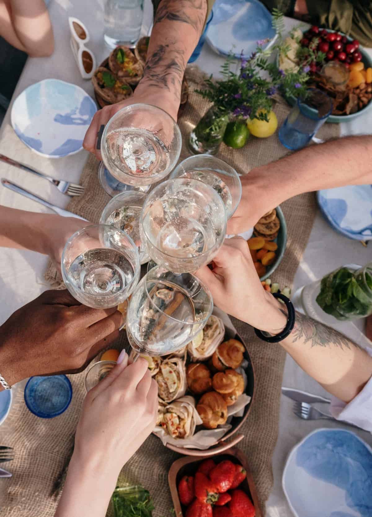 Top view of a group of people toasting their glasses at brunch.