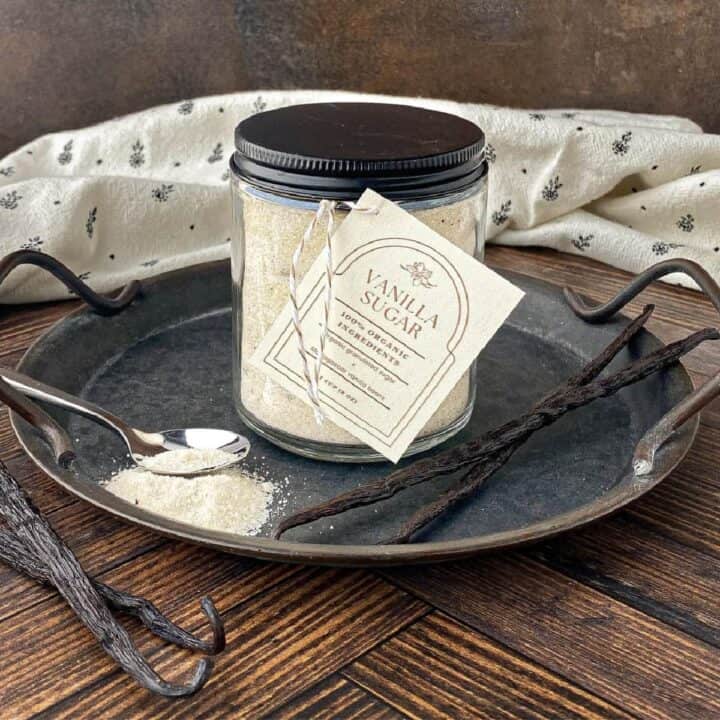 Jar of Vanilla Sugar on a metal tray with vanilla beans.
