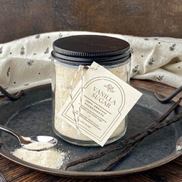 Jar of Vanilla Sugar on a metal tray with vanilla beans.