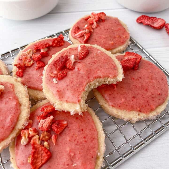Strawberry Shortbread Cookies with Strawberry Glaze on a cooling rack, one with a bite missing.