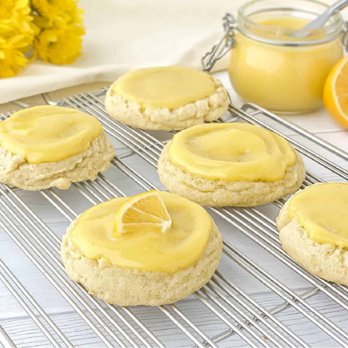 Lemon Curd Cookies on a silver cooling rack with a jar of homemade lemon curd in the background.