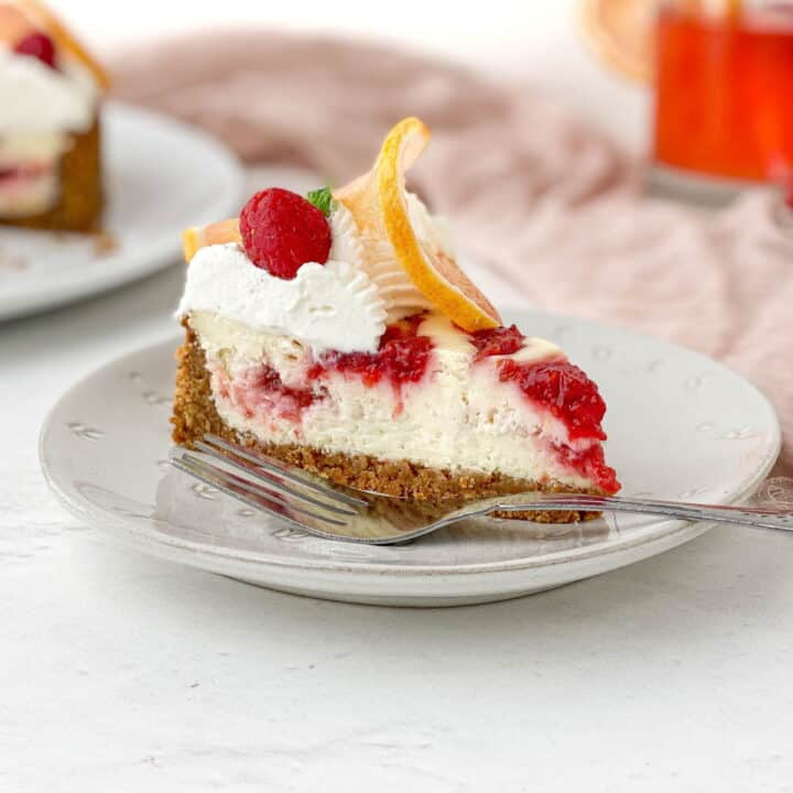 Slice of Raspberry Lemon Cheesecake on a white plate.
