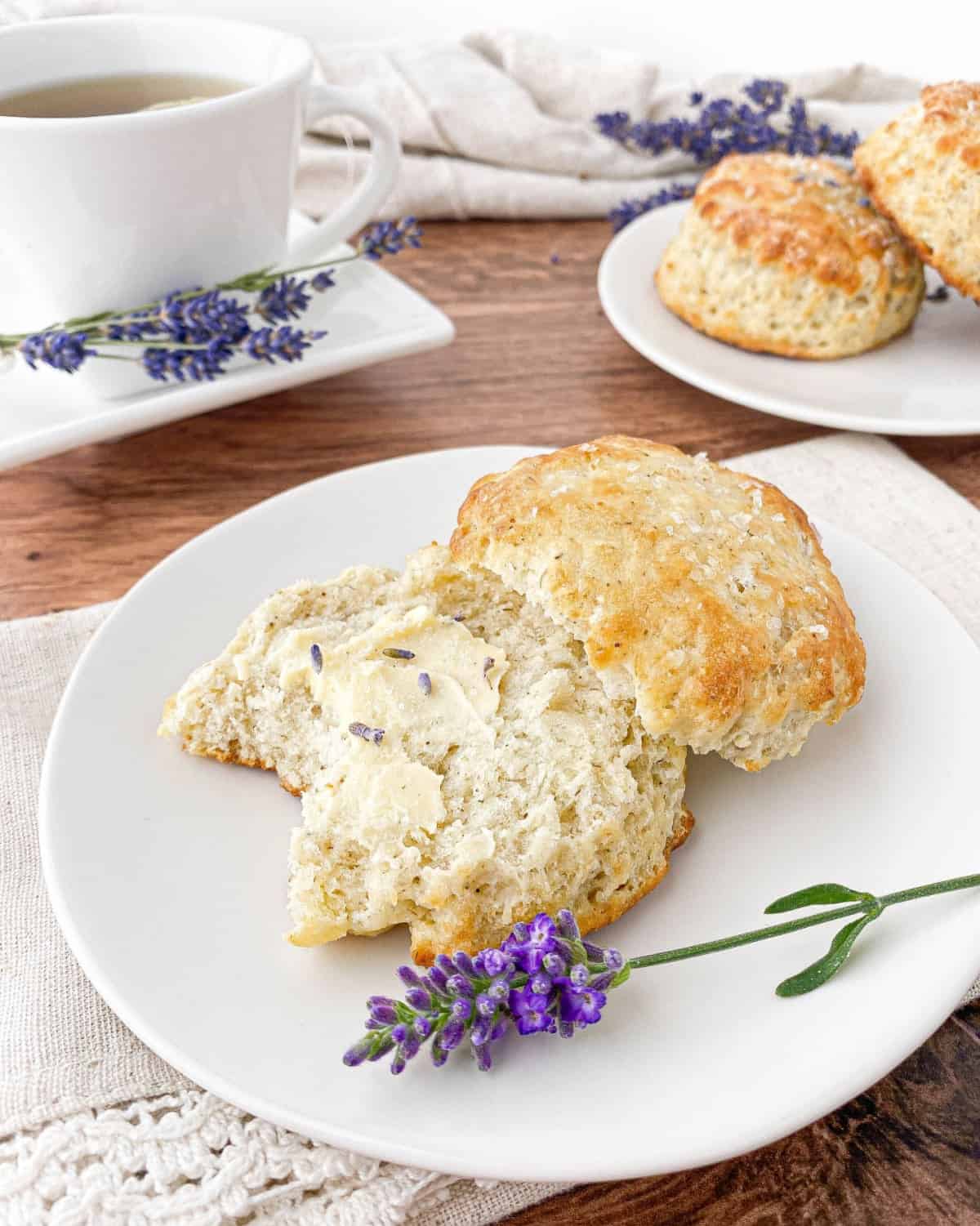 Lavender Biscuit with butter on a white plate with a bite missing.
