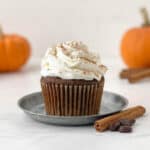 Pumpkin Spice Latte Cupcake on a small galvanized metal plate with a cinnamon stick and coffee beans alongside.