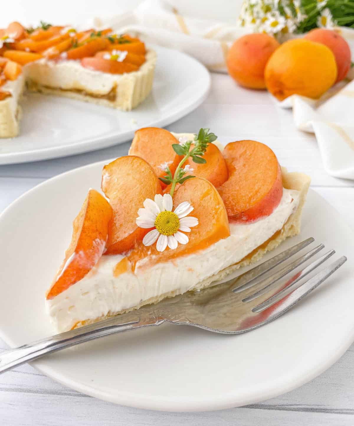 Slice of Apricot Tart on a white plate with a silver fork alongside.