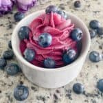 Blueberry Buttercream in a white cup with fresh blueberries on top.
