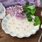 White fluted plate with sugar and lilac blossoms.