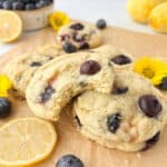 Lemon Blueberry Cookies stacked on parchment paper, one with a bite missing.
