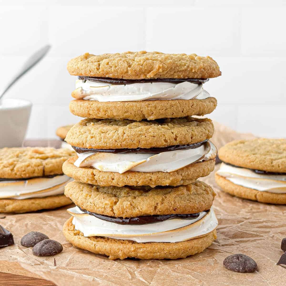 S'mores Cookies stacked on parchment paper with chocolate chips in the foreground.