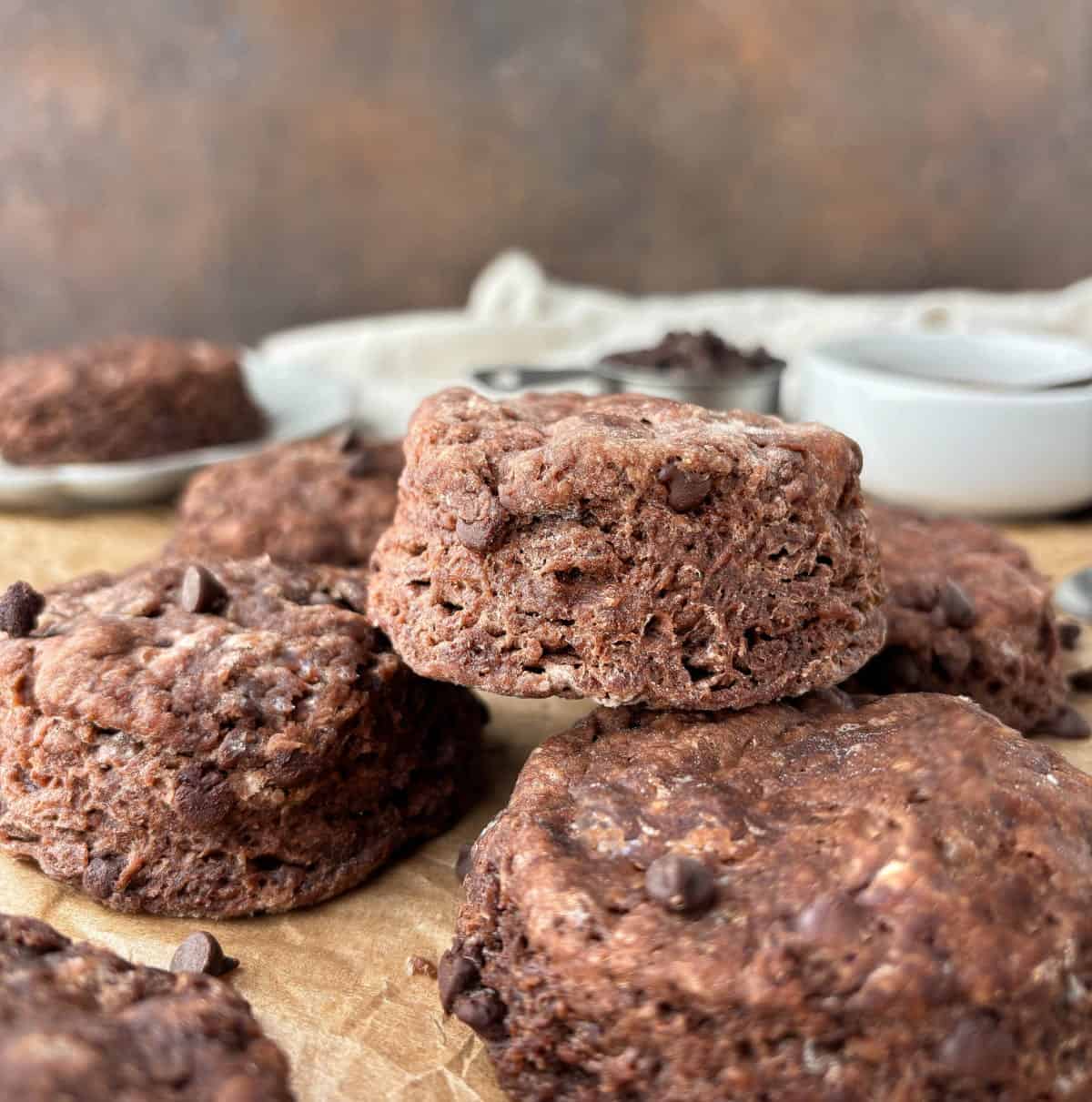A closeup of Chocolate Biscuits stacked on parchment paper.