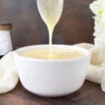 A silver spoon drizzling Cream Cheese Glaze into a small white bowl.